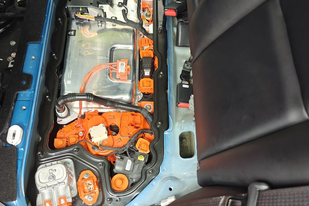 High-voltage battery and orange HV connectors exposed under the rear seat of a Tesla during service at Iron Wolf Motors in Worcester, MA