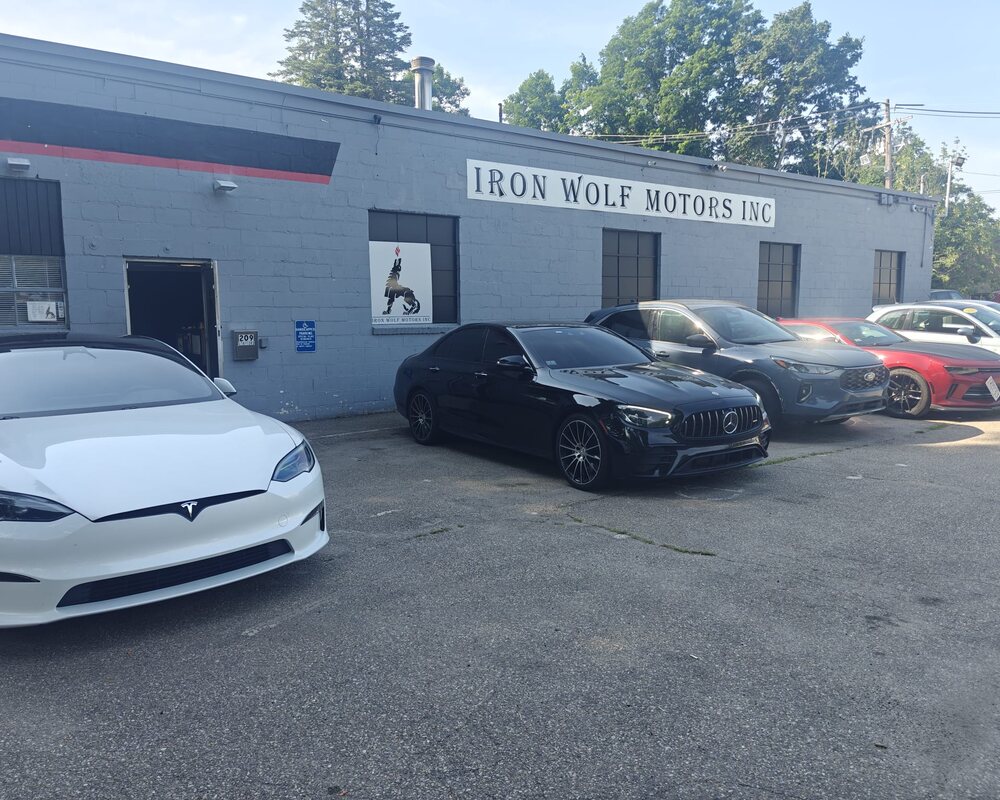The Iron Wolf Motors shop in Worcester, MA — a Tesla Model S and Mercedes-AMG parked out front under the signed storefront