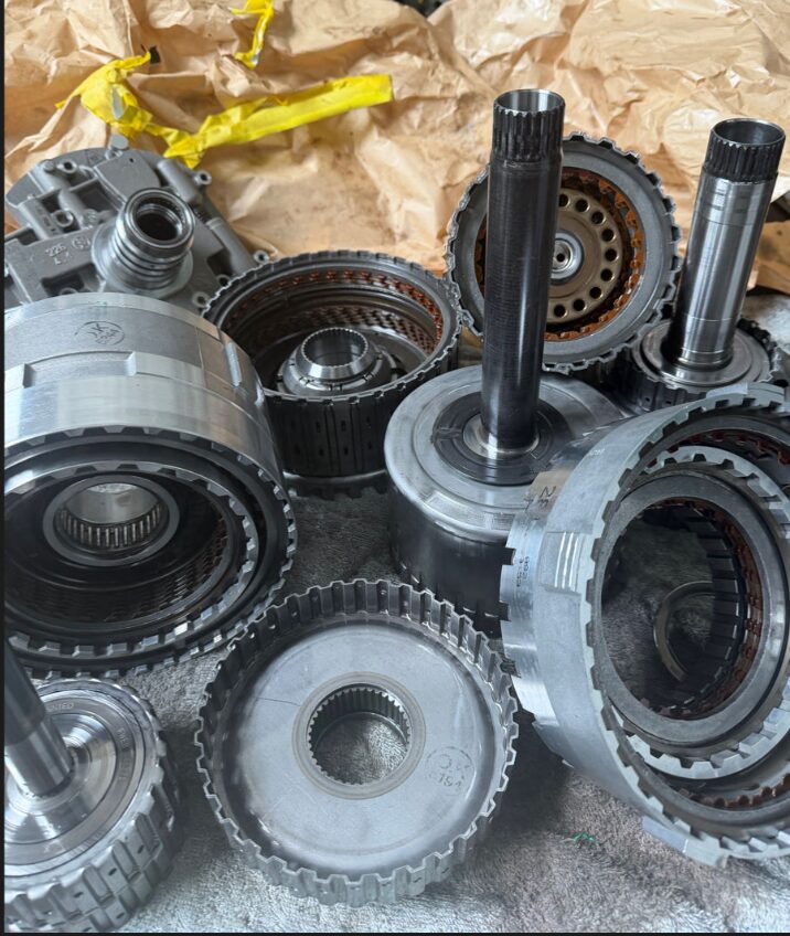 Disassembled automatic transmission internals — clutch packs, drums and sprockets — on the bench at Iron Wolf Motors in Worcester, MA