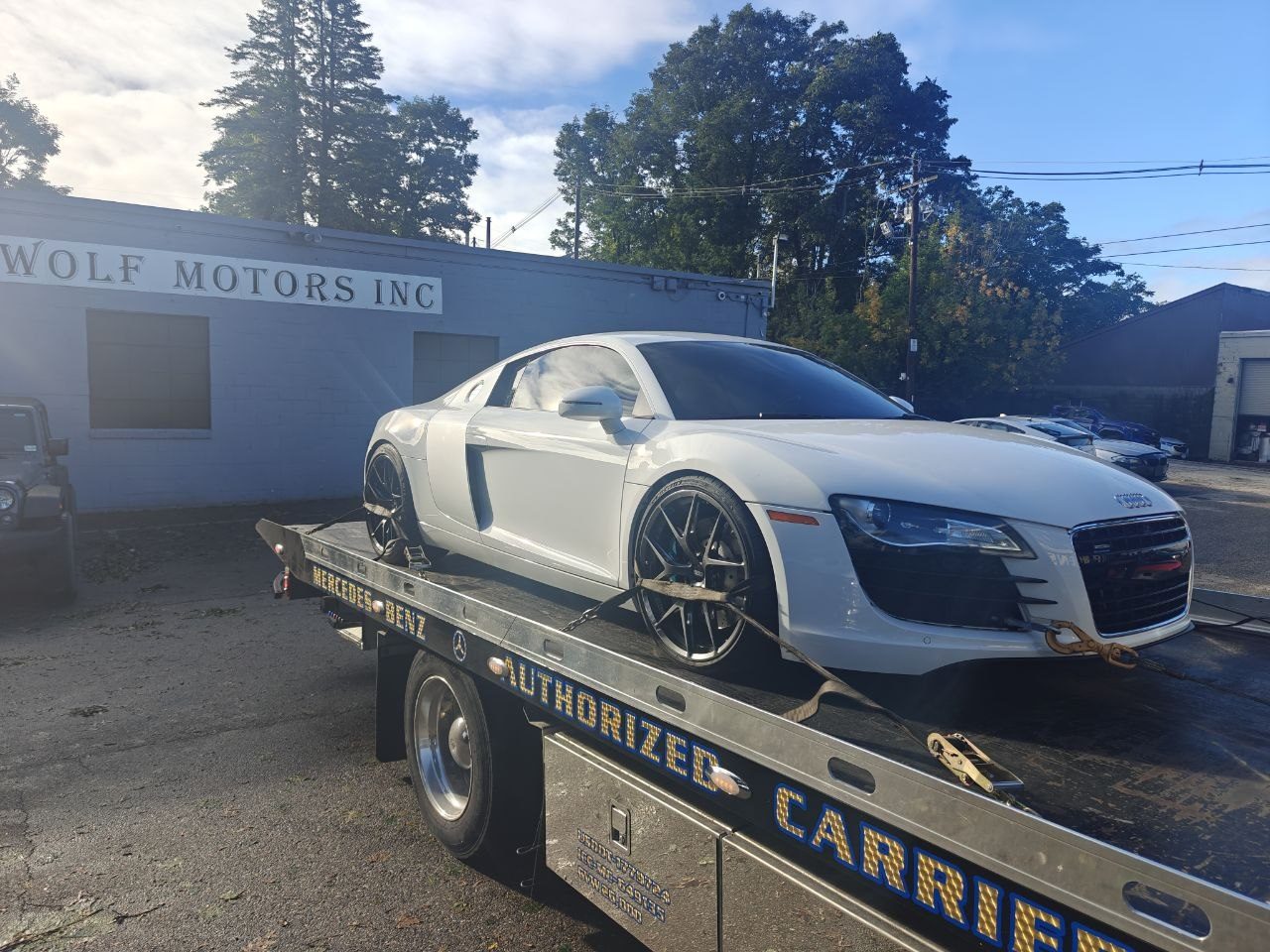 White first-generation Audi R8 strapped to a flatbed tow truck outside Iron Wolf Motors in Worcester, MA, arriving as a no-start