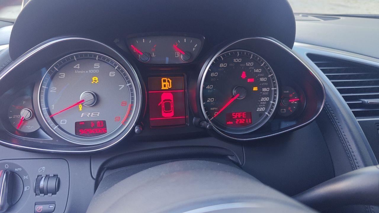 Instrument cluster of an Audi R8 during ECU and immobilizer programming, with the voltmeter reading around 14 volts and warning lamps lit