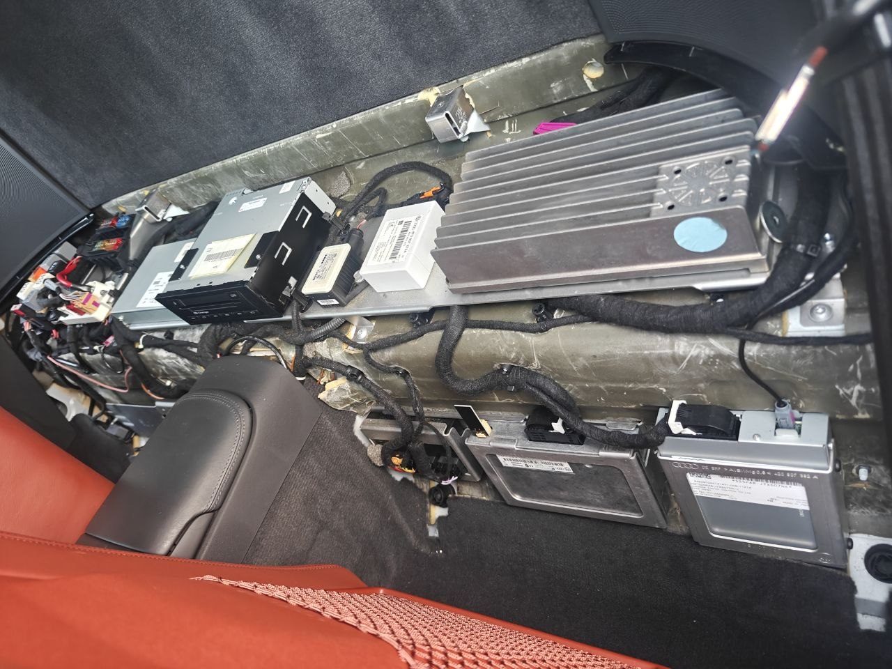 Control modules and wiring in the compartment behind the seats of an Audi R8 with the trim removed