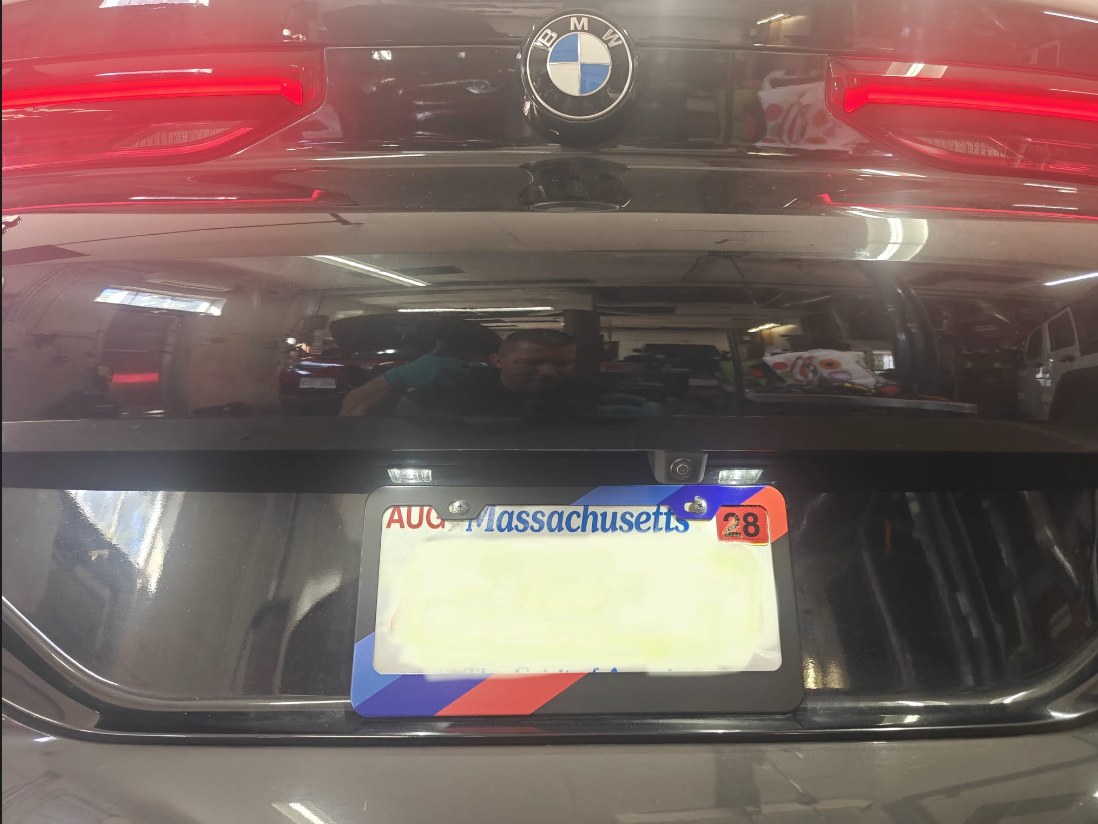 Rear of the BMW X6 with both license plate lights on above a blurred Massachusetts plate