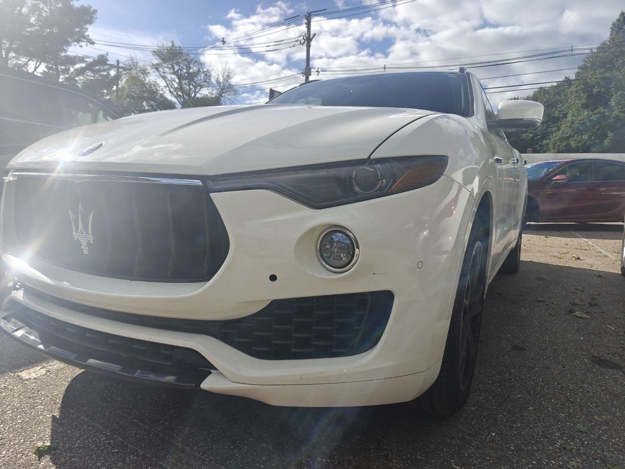 White 2017 Maserati Levante in the lot at Iron Wolf Motors in Worcester, MA, photographed low from the front corner on arrival for a wheel alignment
