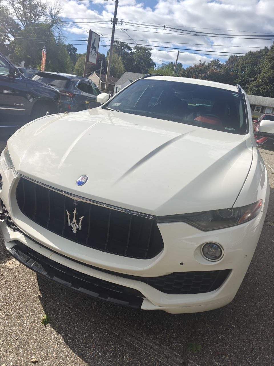 White 2017 Maserati Levante parked in the lot at Iron Wolf Motors on Stafford Street in Worcester, MA, viewed from the front with the shop sign behind it