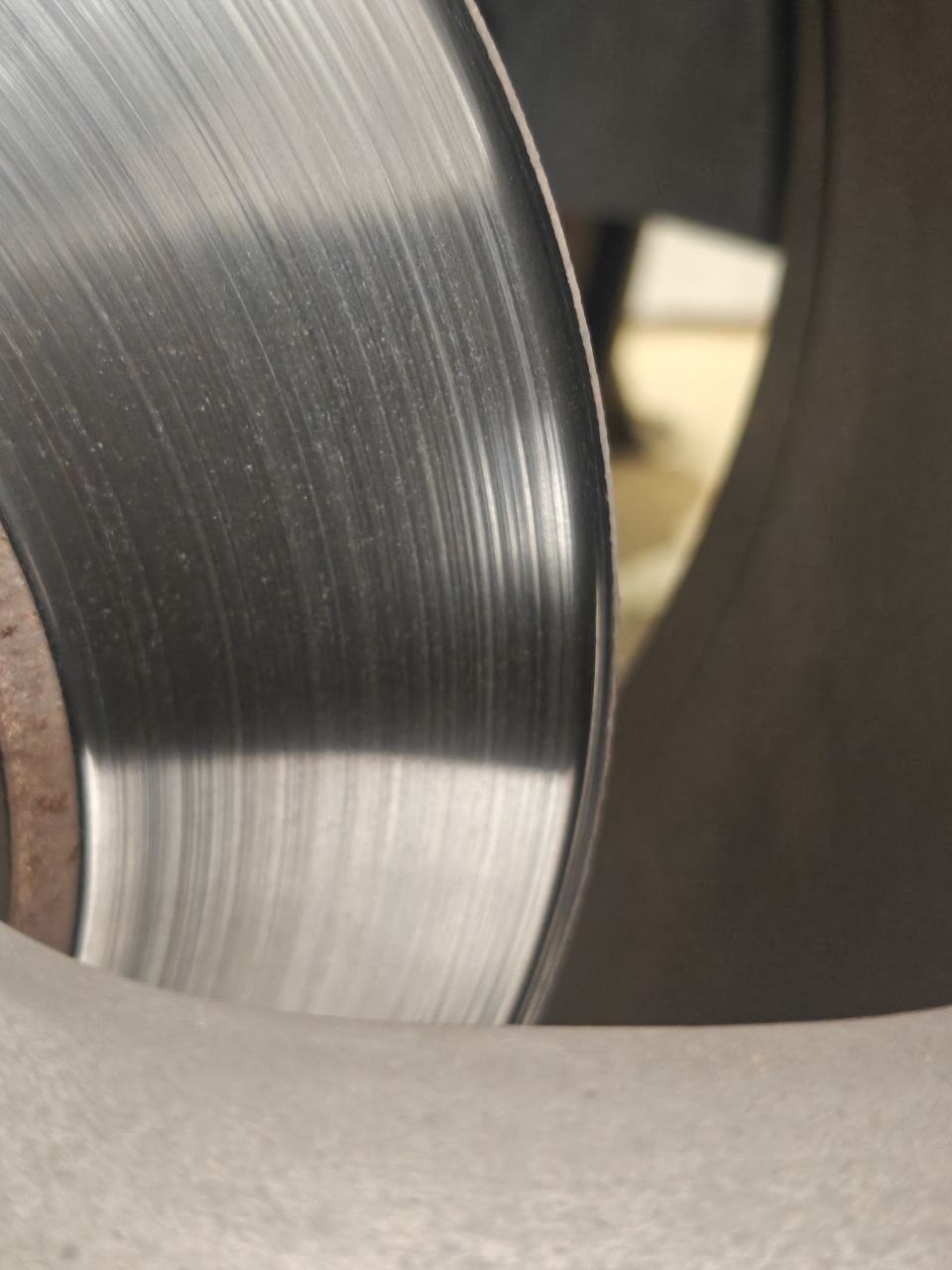 Close-up of a worn front brake rotor on a 2017 Maserati Levante showing a pronounced raised lip around the outer edge and deep concentric grooves scored across the braking surface