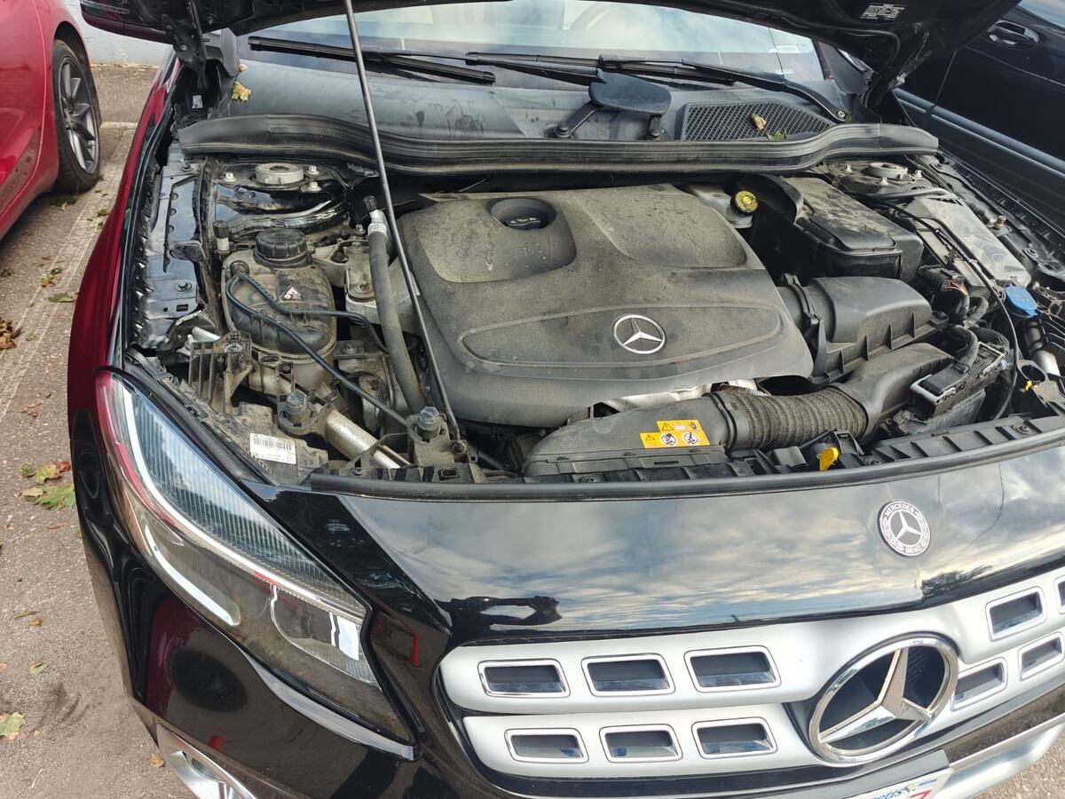 Black Mercedes-Benz GLA250 with the hood raised on arrival at Iron Wolf Motors in Worcester, MA, showing the M270 four-cylinder turbo engine before the oil leak was traced