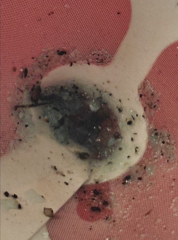 Dark debris and gritty deposits caught in a strainer after draining old coolant from a 2017 Volkswagen Jetta